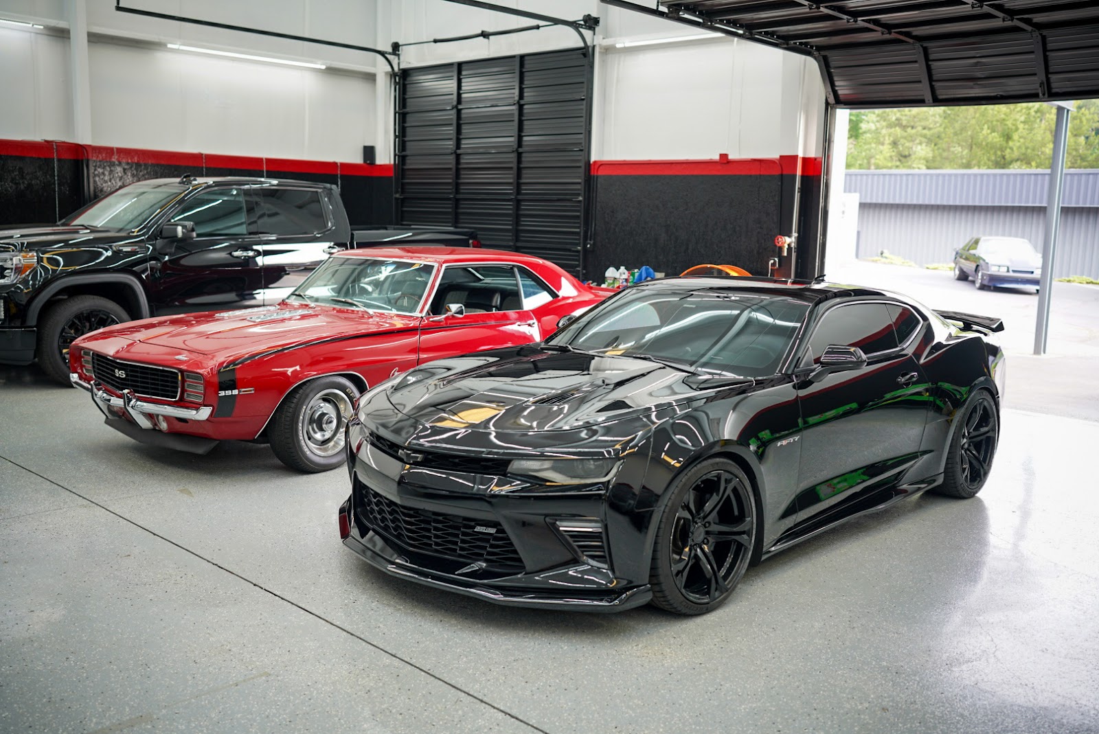 Mendez Body Shop & Collision — a black Camaro and a classic Camaro SS in the bay